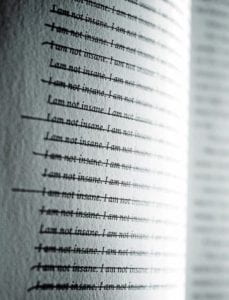 A page of the book with the words 'I am not insane' written and crossed out 145 times