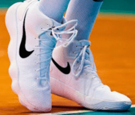 An athlete standing on the court wearing white Nike shoes.